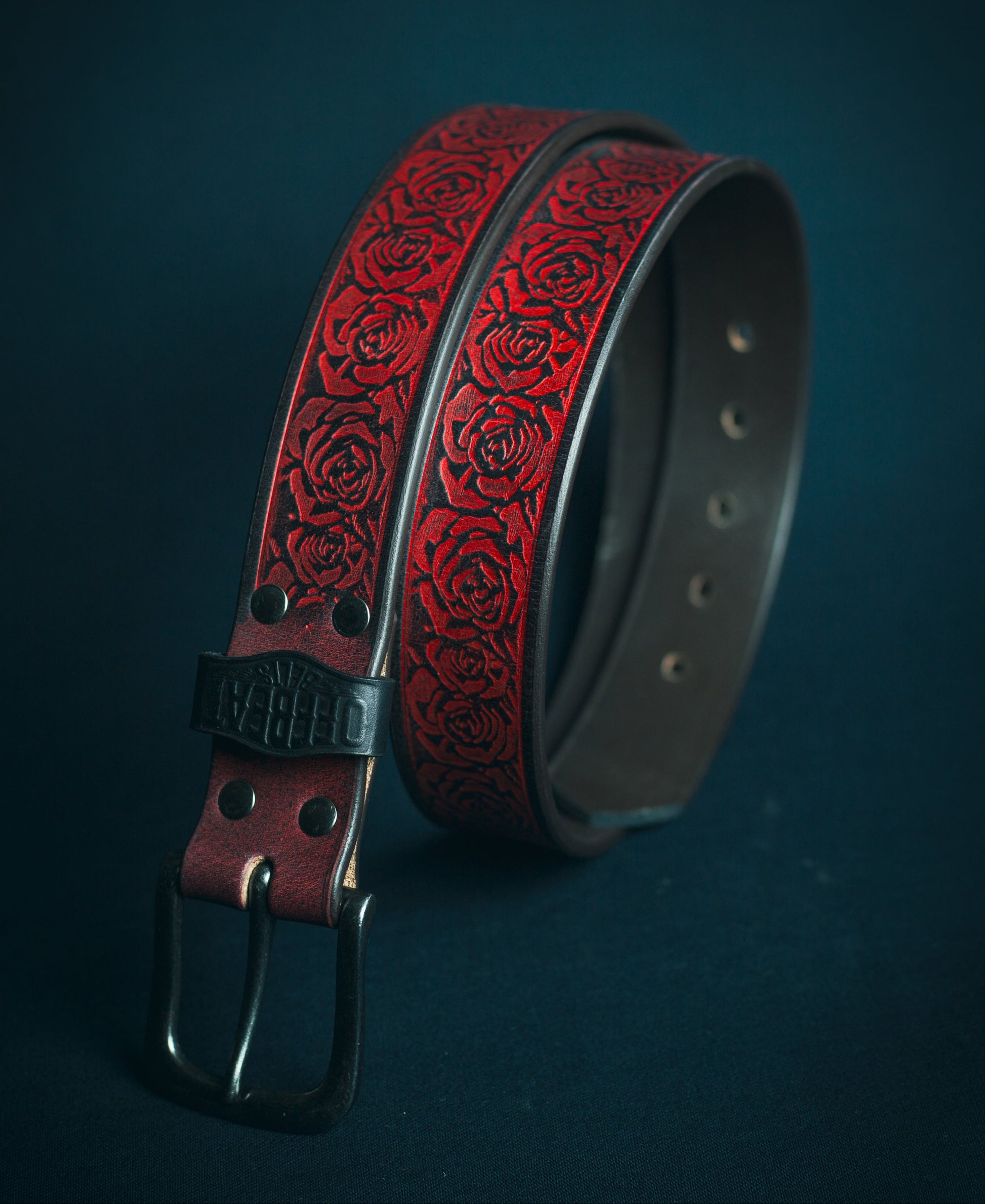 Y2k streetwear black leather belt with red floral embossed design on a dark background