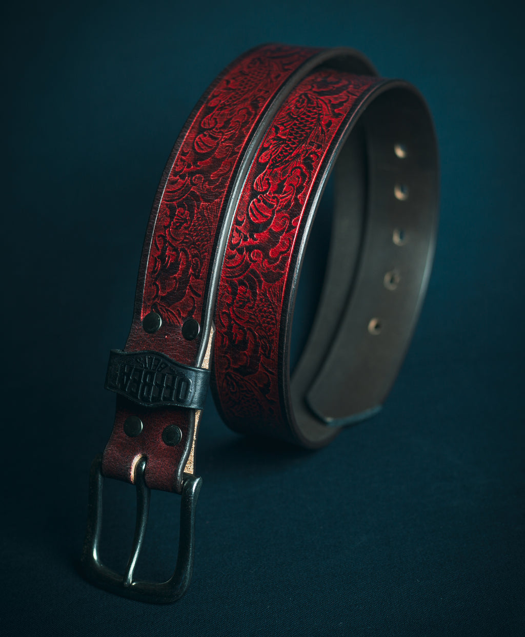 Y2k streetwear black leather belt with red japanese fish embossed design on a dark background