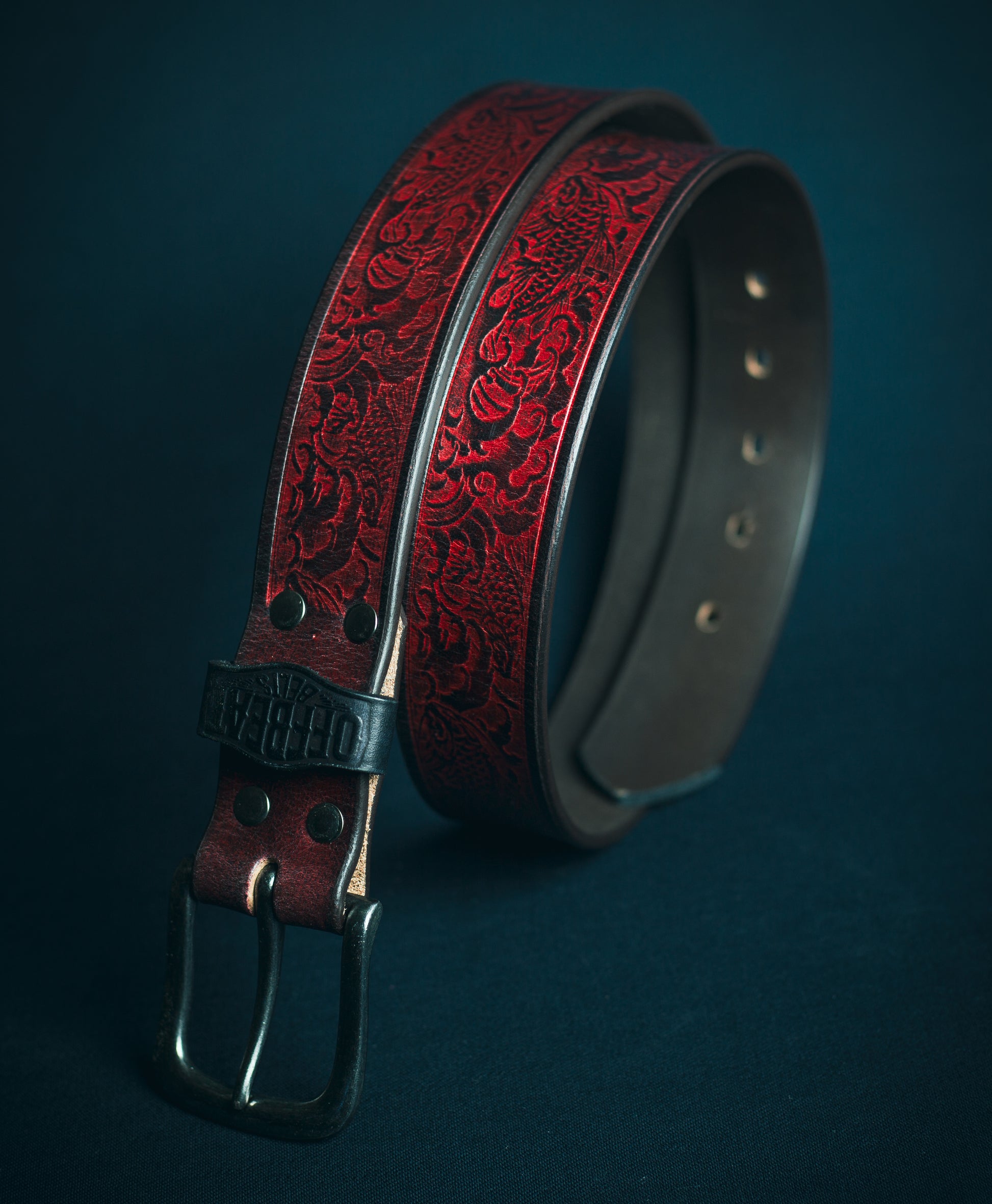 Y2k streetwear black leather belt with red japanese fish embossed design on a dark background