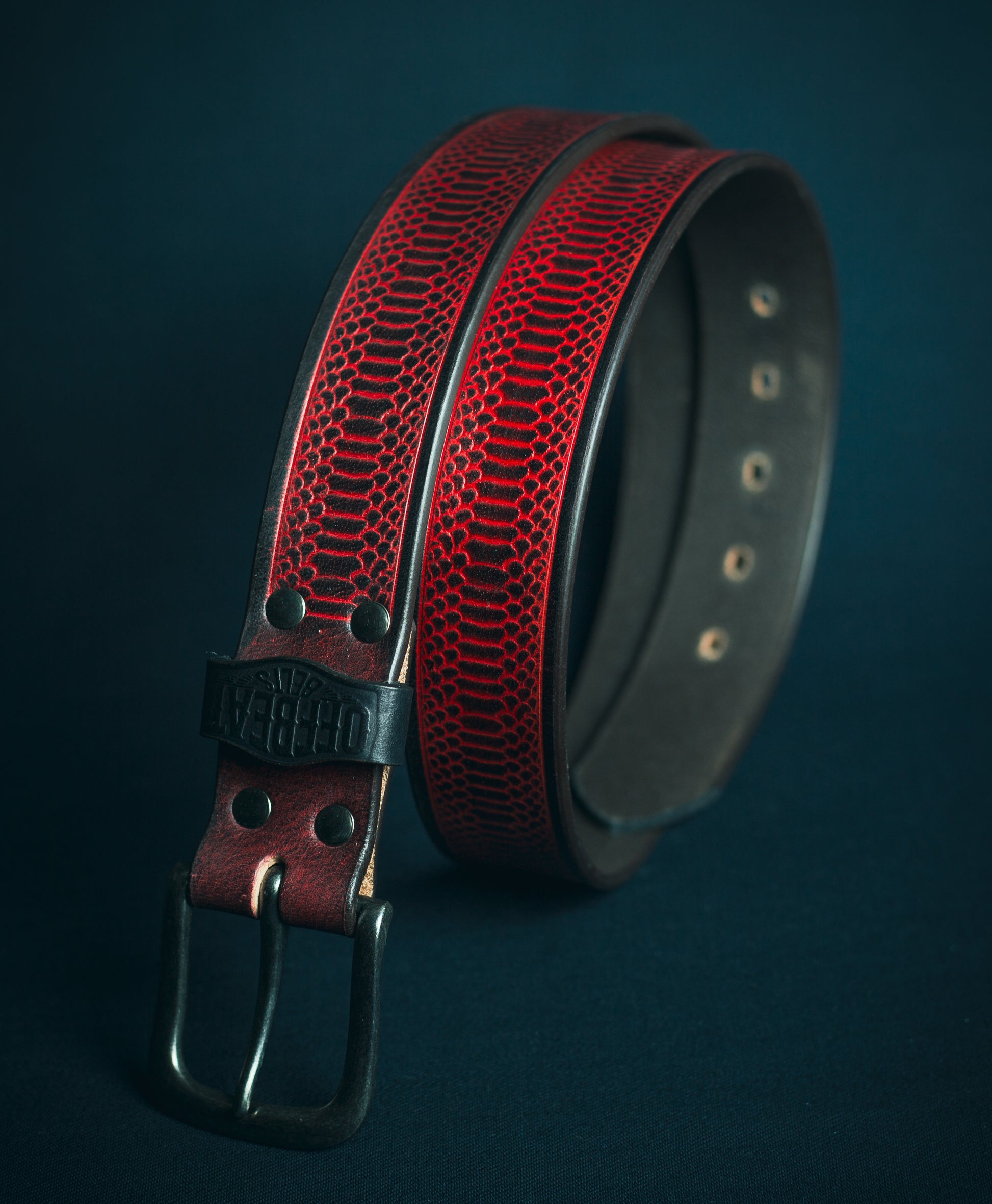 Y2k streetwear red leather belt with black snake embossed design on a dark background